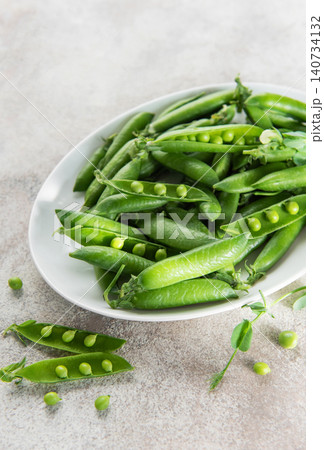 Fresh green peas and pods on white plate 140734132