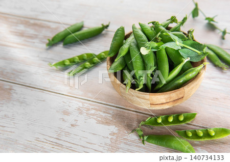 Fresh green pea pods in wooden bowl Fresh green pea pods in wooden bowl 140734133