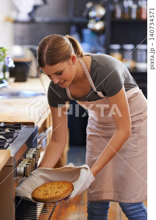 Bakery, oven and woman in kitchen cooking a pie as a chef at restaurant or hotel. Person, smile and baker preparing food in catering business with dinner or lunch dish and skill of baking pastry Bakery, oven and woman in kitchen cooking a pie as a chef at restaurant or hotel. Person, smile and baker preparing food in catering business with dinner or lunch dish and skill of baking pastry 140734371