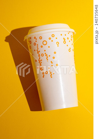 White Disposable Paper Coffee Cup With Lid Casting Shadow, Isolated On Bright Yellow Background White Disposable Paper Coffee Cup With Lid Casting Shadow, Isolated On Bright Yellow Background 140735648