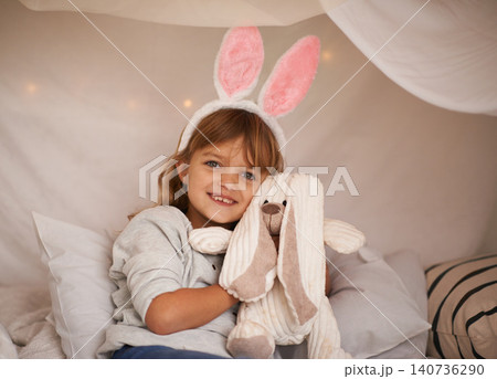 Girl, kid and bunny ears with teddy bear, soft toys and playing in fort for camping and fun at family home. Happiness, innocent and child with stuffed animal, games for Easter and fun in childhood 140736290