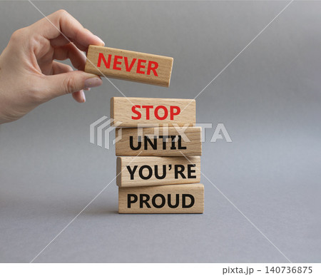 Never Stop symbol. Wooden blocks with words Never Stop Until You are Proud. Businessman hand. Beautiful grey background. Business and Never Stop concept. Copy space Never Stop symbol. Wooden blocks with words Never Stop Until You are Proud. Businessman hand. Beautiful grey background. Business and Never Stop concept. Copy space 140736875