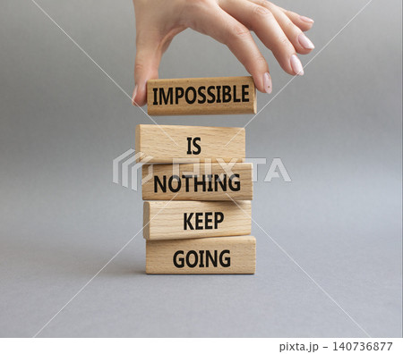 Keep Going symbol. Wooden blocks with words Impossible is Nothing Keep Going. Businessman hand. Beautiful grey background. Business and Keep Going concept. Copy space Keep Going symbol. Wooden blocks with words Impossible is Nothing Keep Going. Businessman hand. Beautiful grey background. Business and Keep Going concept. Copy space 140736877