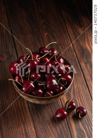 Fresh red cherries filling ceramic bowl on rustic wood 140737029
