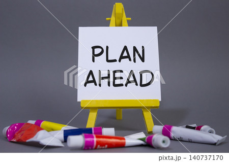 Plan ahead symbol. Wooden blocks with words Plan ahead. Beautiful grey background with paints and easel. Business and Plan ahead concept. Copy space. 140737170