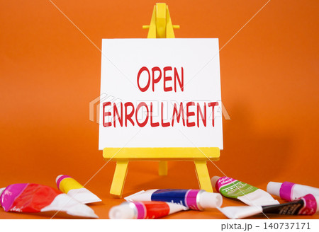 Open Enrollment symbol. Wooden blocks with words Open Enrollment. Beautiful orange background with paints and easel. Business and Open Enrollment concept. Copy space. 140737171