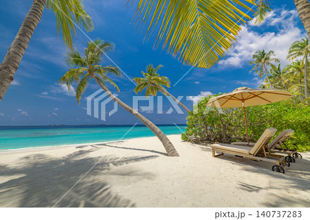Beautiful panoramic ocean sand sky. Tropical relax beach sunny summer island landscape. Love couple sunbeds umbrella palms romantic coast. Luxury travel destination. Honeymoon vacation best holiday Beautiful panoramic ocean sand sky. Tropical relax beach sunny summer island landscape. Love couple sunbeds umbrella palms romantic coast. Luxury travel destination. Honeymoon vacation best holiday 140737283