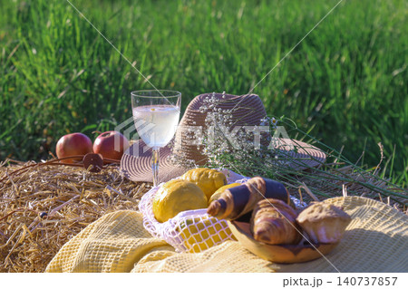 Wine glass and pastries on hay bale in sunny field 140737857