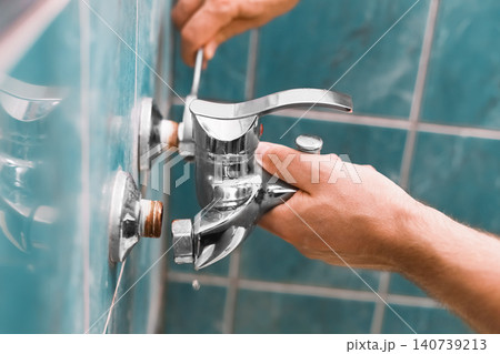 A man is doing repairs during a home renovation. This handyman and homeowner handles DIY repairs and plumbing, replacing an old faucet for a complete faucet replacement. A man is doing repairs during a home renovation. This handyman and homeowner handles DIY repairs and plumbing, replacing an old faucet for a complete faucet replacement. 140739213
