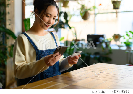 テーブルでカード決済する若い女性 テーブルでカード決済する若い女性 140739597