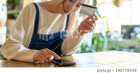 スマホとカードで決済する若い女性 スマホとカードで決済する若い女性 140739599