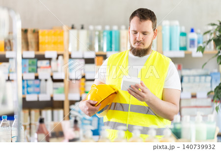Young man builder chooses pills at pharmacy Young man builder chooses pills at pharmacy 140739932