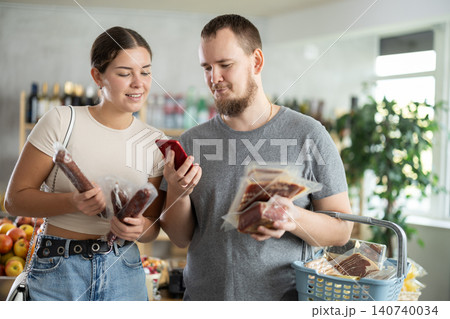 Couple man and woman choosing dried sausages and jamon Couple man and woman choosing dried sausages and jamon 140740034