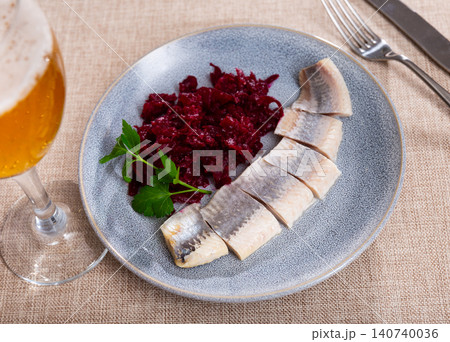 On round blue plate - lightly salted herring fillet cut into pieces with stewed beets 140740036