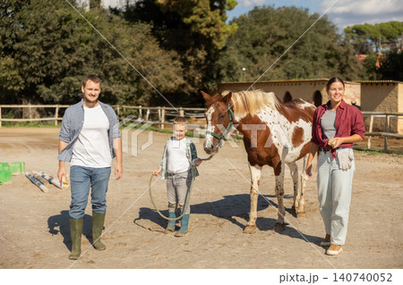 Father, mother and son riding horse together at small horse farm Father, mother and son riding horse together at small horse farm 140740052