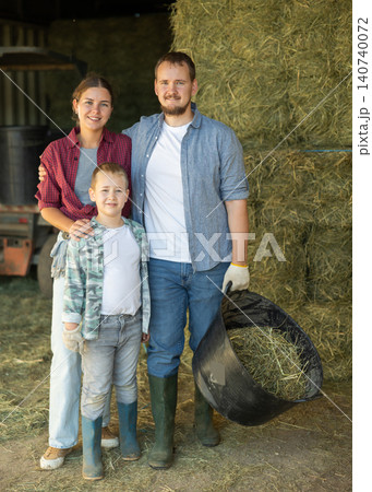Man, woman and boy with bucket of hay in barn Man, woman and boy with bucket of hay in barn 140740072