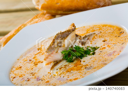 Tasty soup with white fish pollock and greens at white plate 140740083