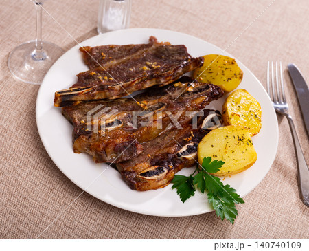 Spanish cuisine churrasco de ternera, spare ribs with potatoes on ceramic plate Spanish cuisine churrasco de ternera, spare ribs with potatoes on ceramic plate 140740109