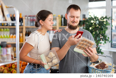 Spouses inspects oyster mushrooms and champignons, photographs QR code on label by smartphone Spouses inspects oyster mushrooms and champignons, photographs QR code on label by smartphone 140740169