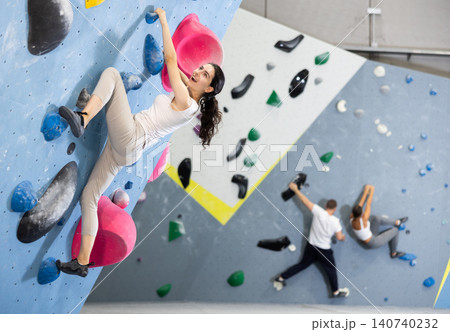 Young woman doing rock climbing on climbing wall Young woman doing rock climbing on climbing wall 140740232