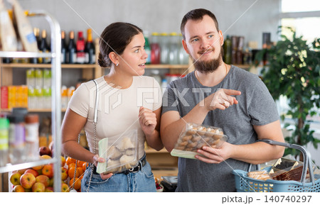 Husband and wife choose mushrooms together in supermarket - family chooses mushrooms: oyster mushrooms or champignons Husband and wife choose mushrooms together in supermarket - family chooses mushrooms: oyster mushrooms or champignons 140740297