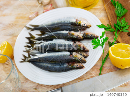 Fresh sardines lying on plate with lemon, parsley and garlic Fresh sardines lying on plate with lemon, parsley and garlic 140740350