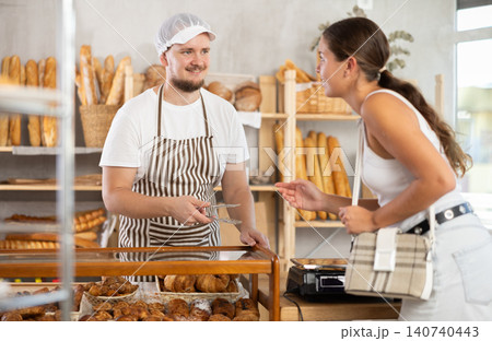 Salesman gives croissants to young girl in bakery 140740443
