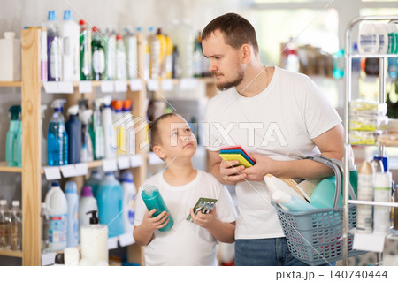 Man and boy choosing household chemicals in store Man and boy choosing household chemicals in store 140740444