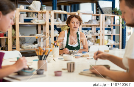 Three craftsperson are busy painting clay products Three craftsperson are busy painting clay products 140740567