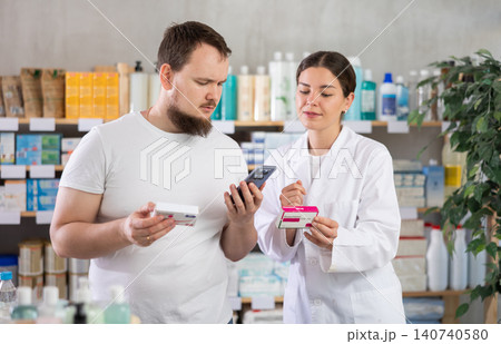 Man scans QR code on box paracetamol pills label. Female pharmacist offers to choose right shampoo Man scans QR code on box paracetamol pills label. Female pharmacist offers to choose right shampoo 140740580
