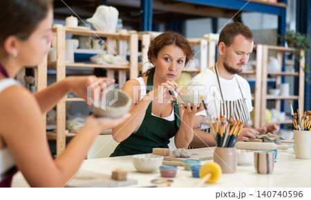 Three pottery workshop workers sculpt from raw clay Three pottery workshop workers sculpt from raw clay 140740596
