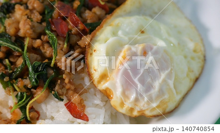 stir fried pork with holy basil on top with fried egg on cooked rice stir fried pork with holy basil on top with fried egg on cooked rice 140740854