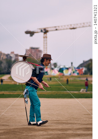 View of a bass drum with a cymbal, a man playing and spinning it, a Chilean chinchinero, a street musician playing the bass drum and dancing in the streets, a Chilean cultural tradition. 140741321