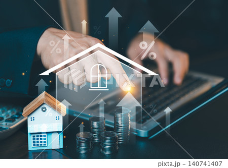 Close up of businessman hand pointing at virtual house icon with rising arrows and stacks of coins on desk. Close up of businessman hand pointing at virtual house icon with rising arrows and stacks of coins on desk. 140741407