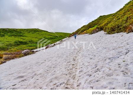 夏の晴天 鳥海山・賽の河原付近の広大な残雪の雪原を歩く登山客の後ろ姿と山岳風景 夏の晴天 鳥海山・賽の河原付近の広大な残雪の雪原を歩く登山客の後ろ姿と山岳風景 140741434