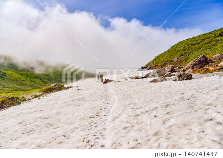 夏の晴天 鳥海山・賽の河原付近の広大な残雪の雪原を歩く登山客の後ろ姿と山岳風景 夏の晴天 鳥海山・賽の河原付近の広大な残雪の雪原を歩く登山客の後ろ姿と山岳風景 140741437