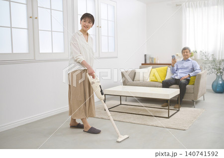 会話をしながら掃除機をかける笑顔の女性と60代の男性 140741592