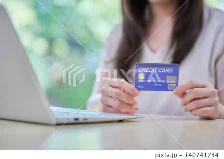 クレジットカードを見ながらパソコン入力する20代の女性 クレジットカードを見ながらパソコン入力する20代の女性 140741734