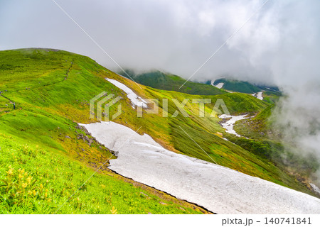 夏の晴れ間 湧き上がる雲に覆われる鳥海山の残雪残る山肌と斜面に流れる雪原風景 夏の晴れ間 湧き上がる雲に覆われる鳥海山の残雪残る山肌と斜面に流れる雪原風景 140741841