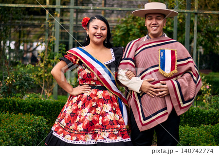 Portrait of a smiling young couple, dressed as Chilean huasos, posing romantically and joyfully to dance cueca, a traditional Chilean dance. Chilean traditions, celebrations, and culture. Portrait of a smiling young couple, dressed as Chilean huasos, posing romantically and joyfully to dance cueca, a traditional Chilean dance. Chilean traditions, celebrations, and culture. 140742774