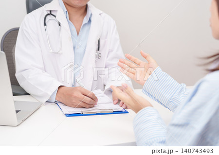 Doctor and patient having a medical consultation in a hospital room, explaining a treatment plan, discussing diagnosis, and giving advice during a medical health checkup appointment in a clinic Doctor and patient having a medical consultation in a hospital room, explaining a treatment plan, discussing diagnosis, and giving advice during a medical health checkup appointment in a clinic 140743493
