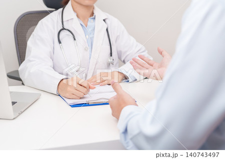 Doctor and patient having a medical consultation in a hospital room, explaining a treatment plan, discussing diagnosis, and giving advice during a medical health checkup appointment in a clinic Doctor and patient having a medical consultation in a hospital room, explaining a treatment plan, discussing diagnosis, and giving advice during a medical health checkup appointment in a clinic 140743497