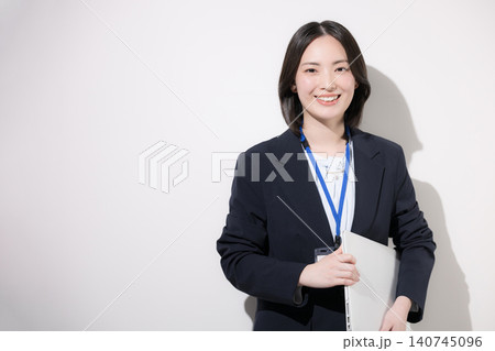 白背景でノートパソコンを持つ笑顔の若手女性会社員 オフィスで働くイメージ　カメラ目線笑顔 140745096