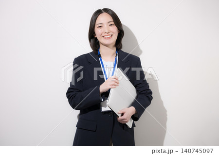 白背景でノートパソコンを持つ笑顔の若手女性会社員 オフィスで働くイメージ　カメラ目線笑顔 140745097