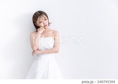 白い背景の前で考えるポーズをするウエディングドレスを着た女性 140745304