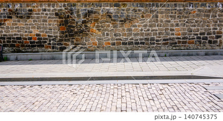 Rustic brick wall beside cobblestone path Rustic brick wall beside cobblestone path 140745375