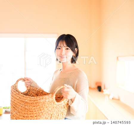 洗濯物を運ぶ笑顔の若い女性のポートレート 洗濯物を運ぶ笑顔の若い女性のポートレート 140745593