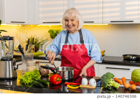 Senior old woman cooking homemade soup in kitchen tasting seasoning for healthy diet family dinner Senior old woman cooking homemade soup in kitchen tasting seasoning for healthy diet family dinner 140746306