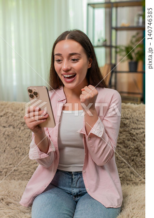 Young woman celebrates contest win after reading positive smartphone message expressing joyful shock Young woman celebrates contest win after reading positive smartphone message expressing joyful shock 140746385