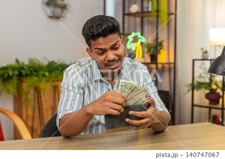 Indian man checks wallet sees small bills low cash sighs plans savings budget goal debt recovery aim Indian man checks wallet sees small bills low cash sighs plans savings budget goal debt recovery aim 140747067